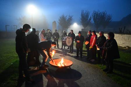 Menschen zünden am Osterfeuer eine Kerze an
